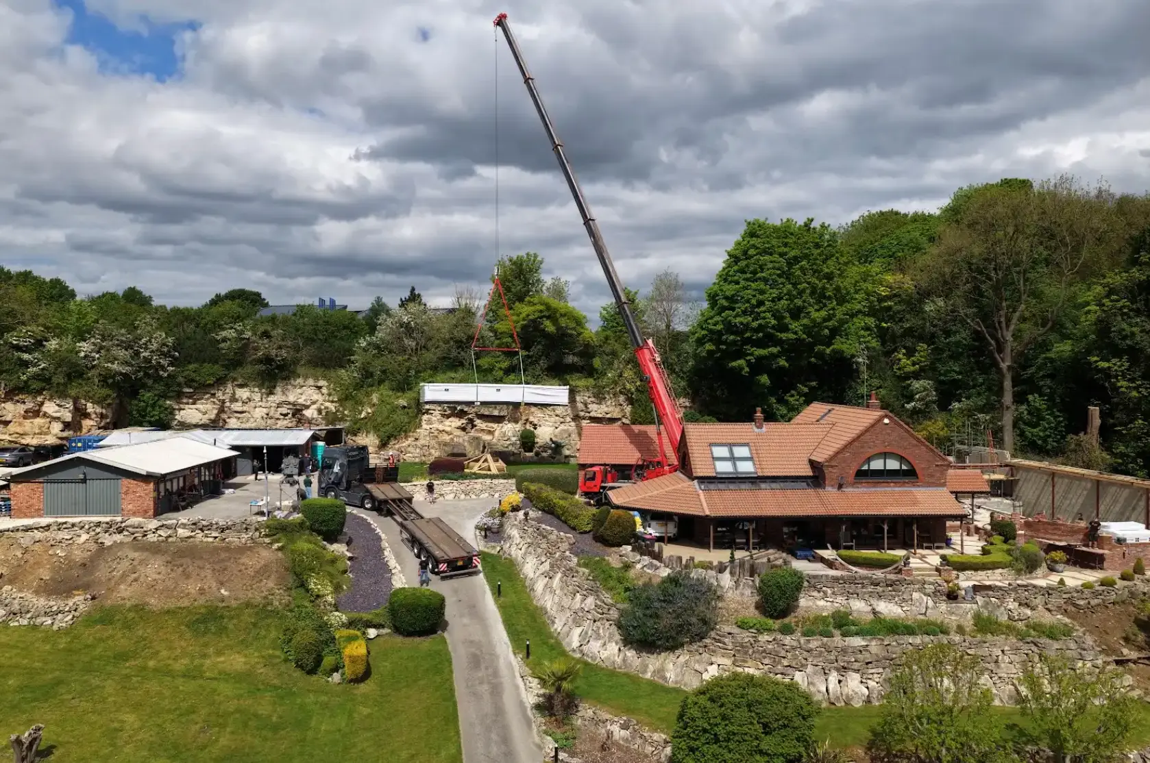 Crane lifting hot tub over a residential garden